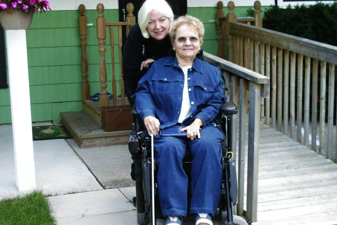 Two women smile for the camera one of who is in a wheelchair.