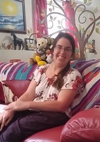 Amy Adair smiling on the couch in her home.